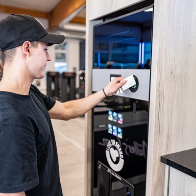Junger Mann holt sich einen Shake aus dem Automaten
