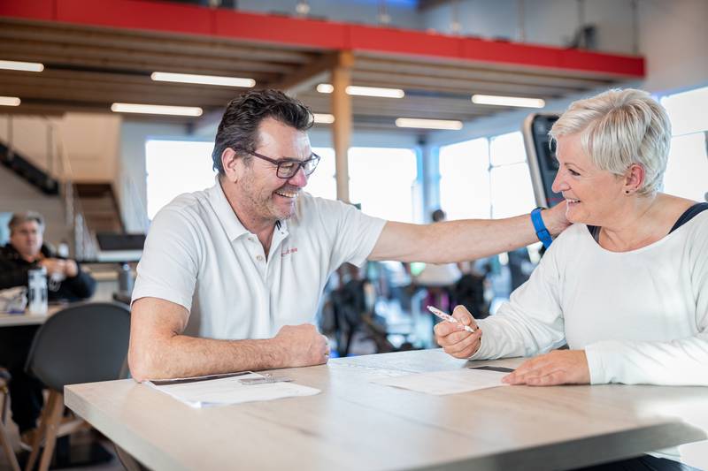 Beratungsgespräch zwischen Trainer und Mitglied am Tisch
