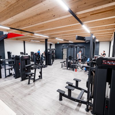 Heller Trainingsraum mit Kraftgeräten und Holzdecke