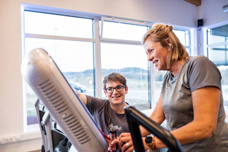 Trainerin erklärt einem Jugendlichen ein Trainingsgerät