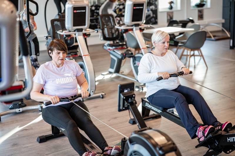Zwei Frauen trainieren gemeinsam auf Rudergeräten