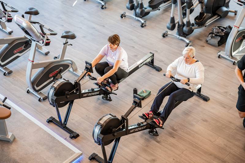 Zwei Personen trainieren gemeinsam auf Rudergeräten